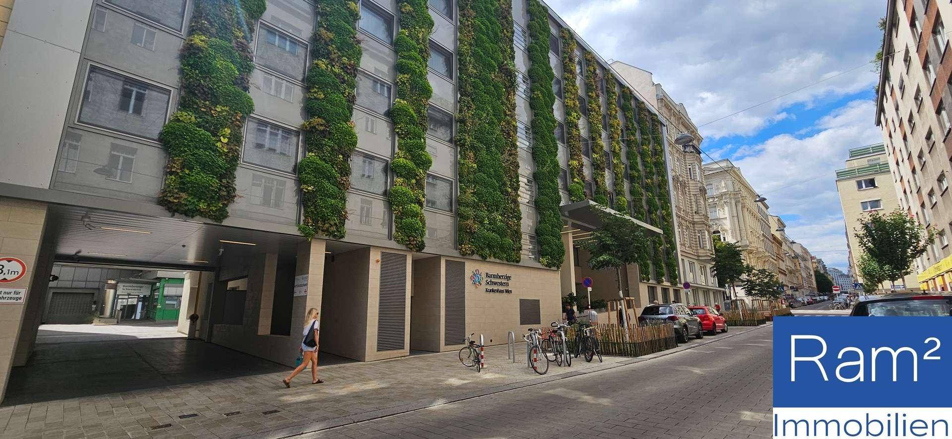 Moderne Gebäudefassade mit vertikalen Grünflächen und einer belebten Straße davor.