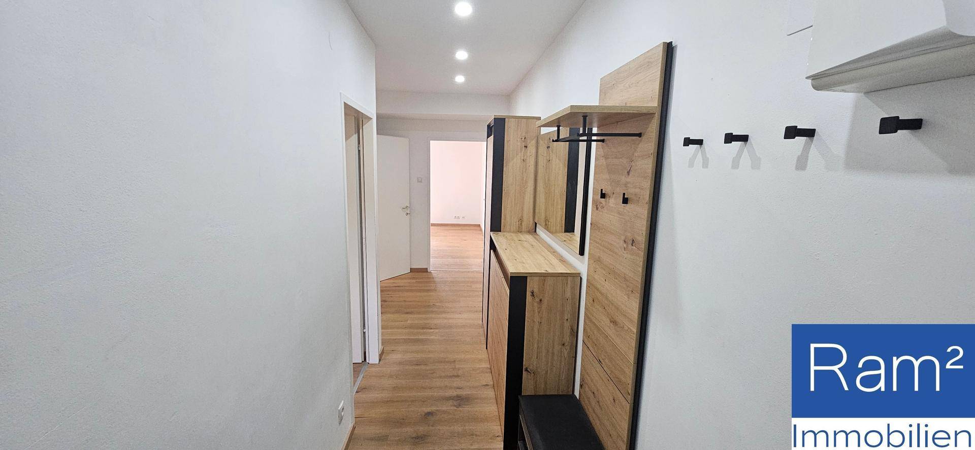 Heller Flur mit Holzfußboden und moderner Garderobe.
