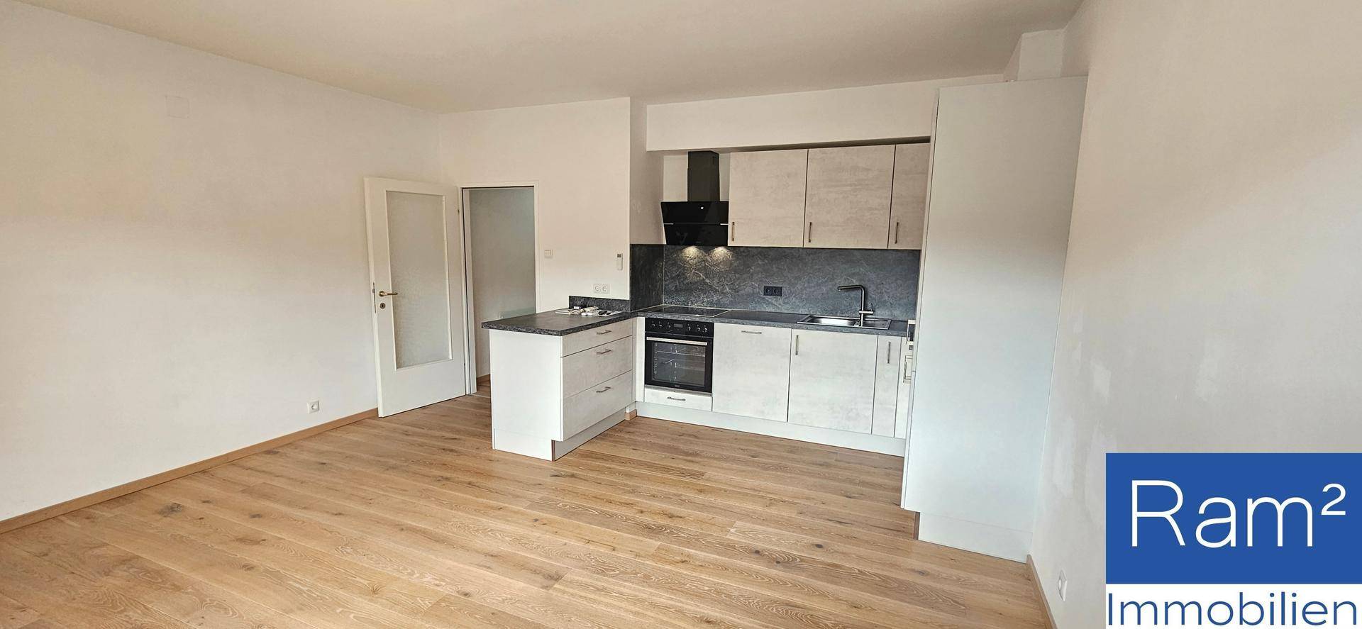 Offener Küchenbereich mit moderner Einbauküche und hellem Holzfußboden.