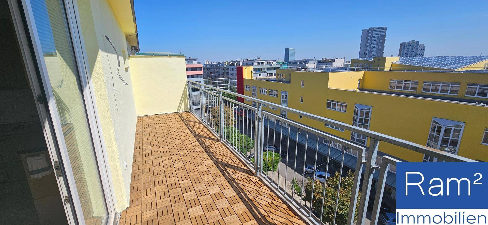Heller Balkon mit Fliesenboden und Metallgeländer, bietet einen weiten Blick über die Stadt.