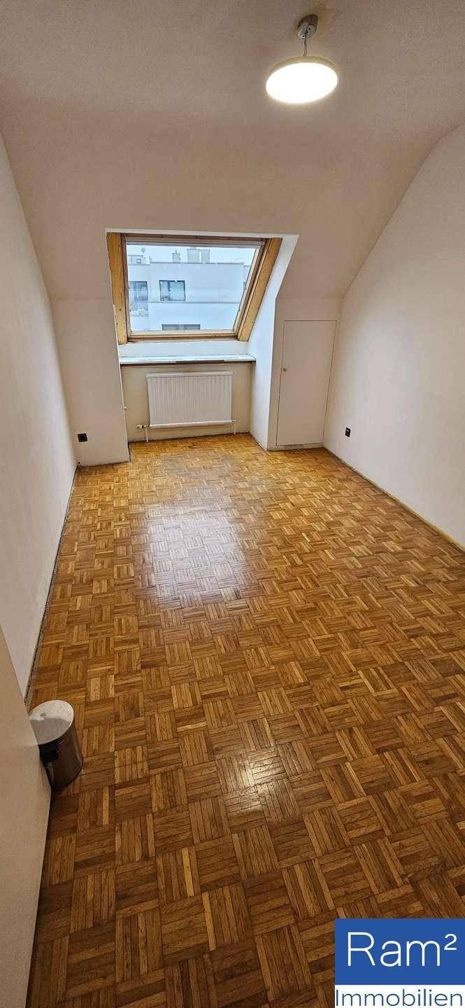 Lichtdurchflutetes Zimmer mit Parkettboden und einem großen Dachschrägenfenster.