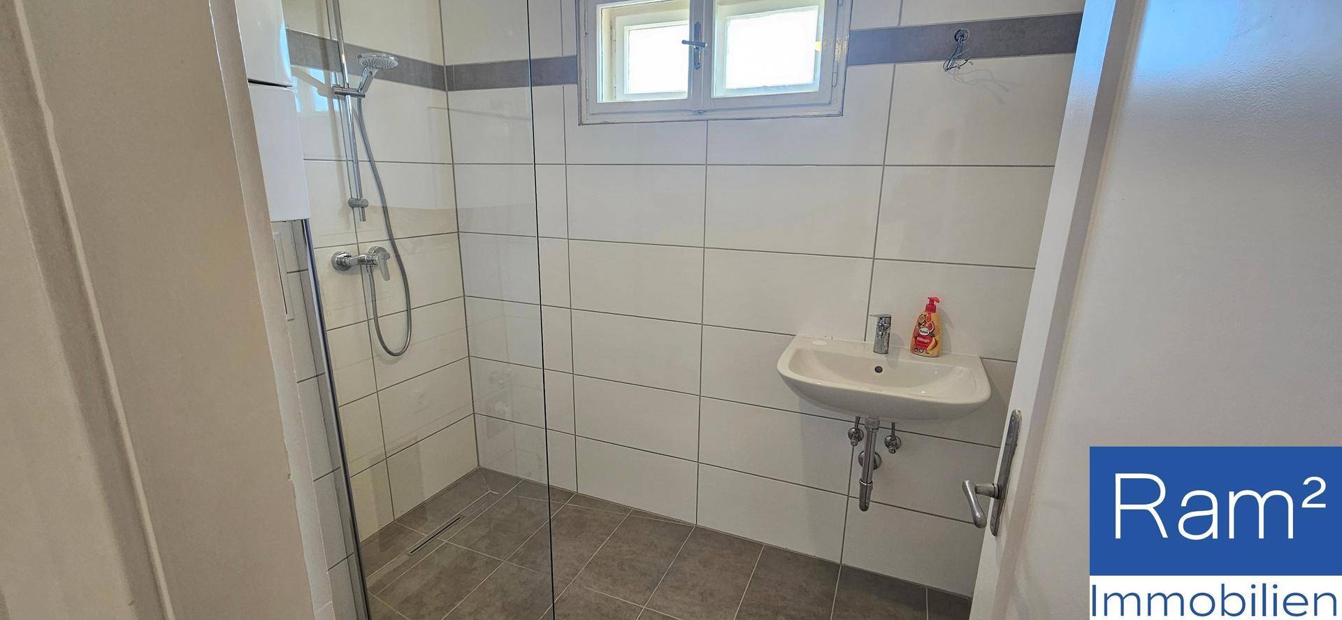 Helles Badezimmer mit begehbarer Dusche, Waschbecken und Fenster für natürliche Belüftung.