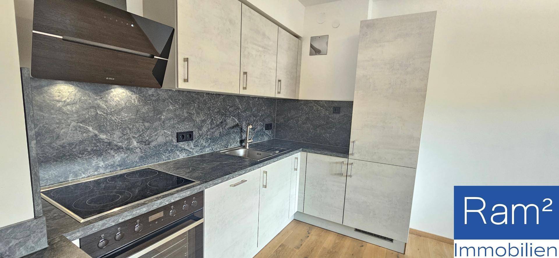 Moderne Einbauküche mit grauen Fronten, dunkler Arbeitsplatte und integrierten Geräten.