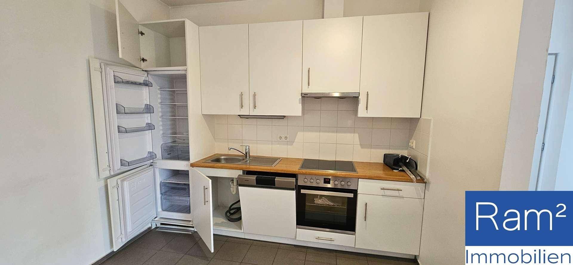 Funktionale Einbauküche mit weißen Schränken, integriertem Backofen und Kühlschrank.