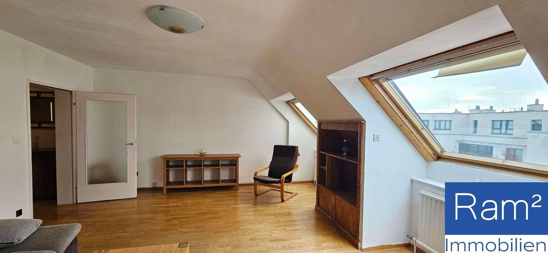 Geräumiges Wohnzimmer mit Holzboden, Dachschrägen und viel Tageslicht durch große Fenster.