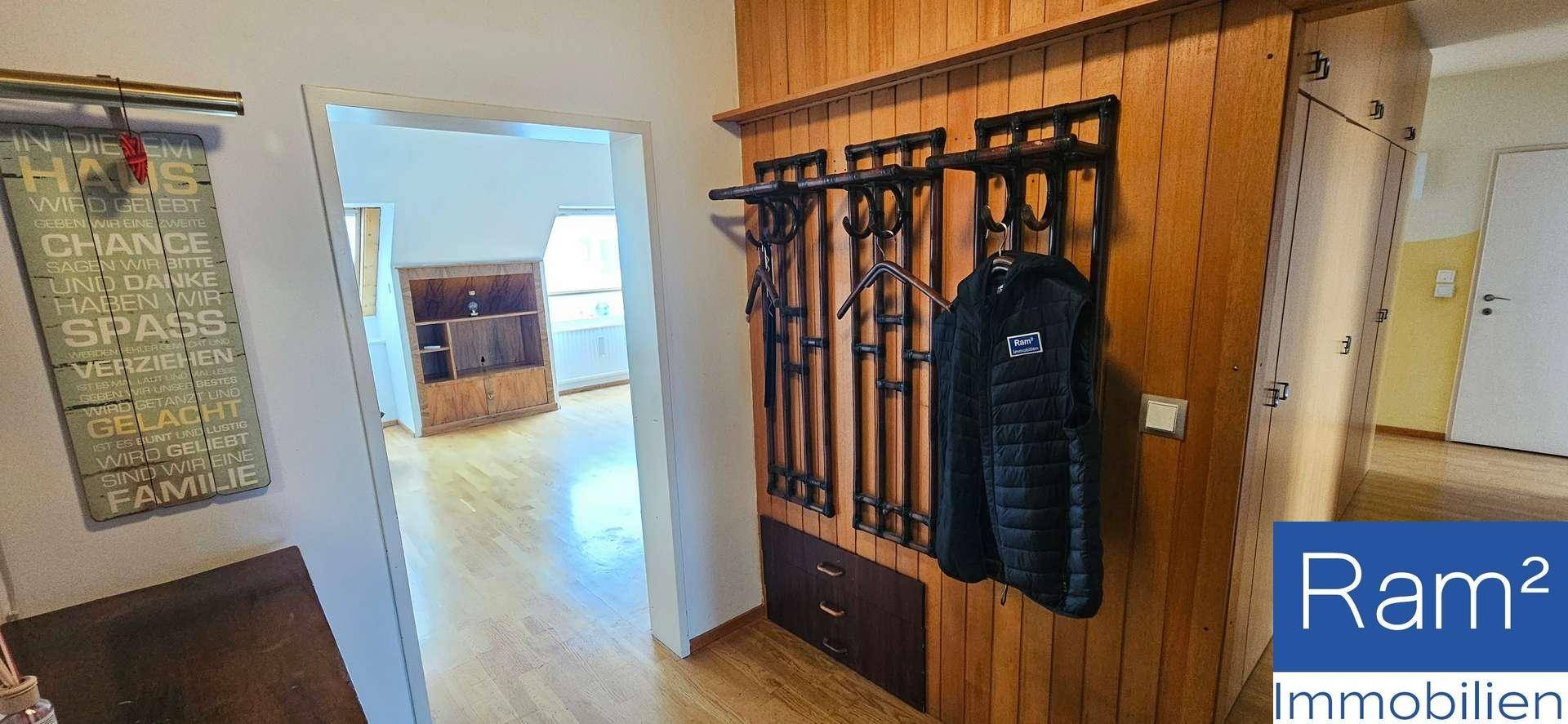 Flur mit Holzvertäfelung und Garderobe, führt in einen hellen Wohnbereich.