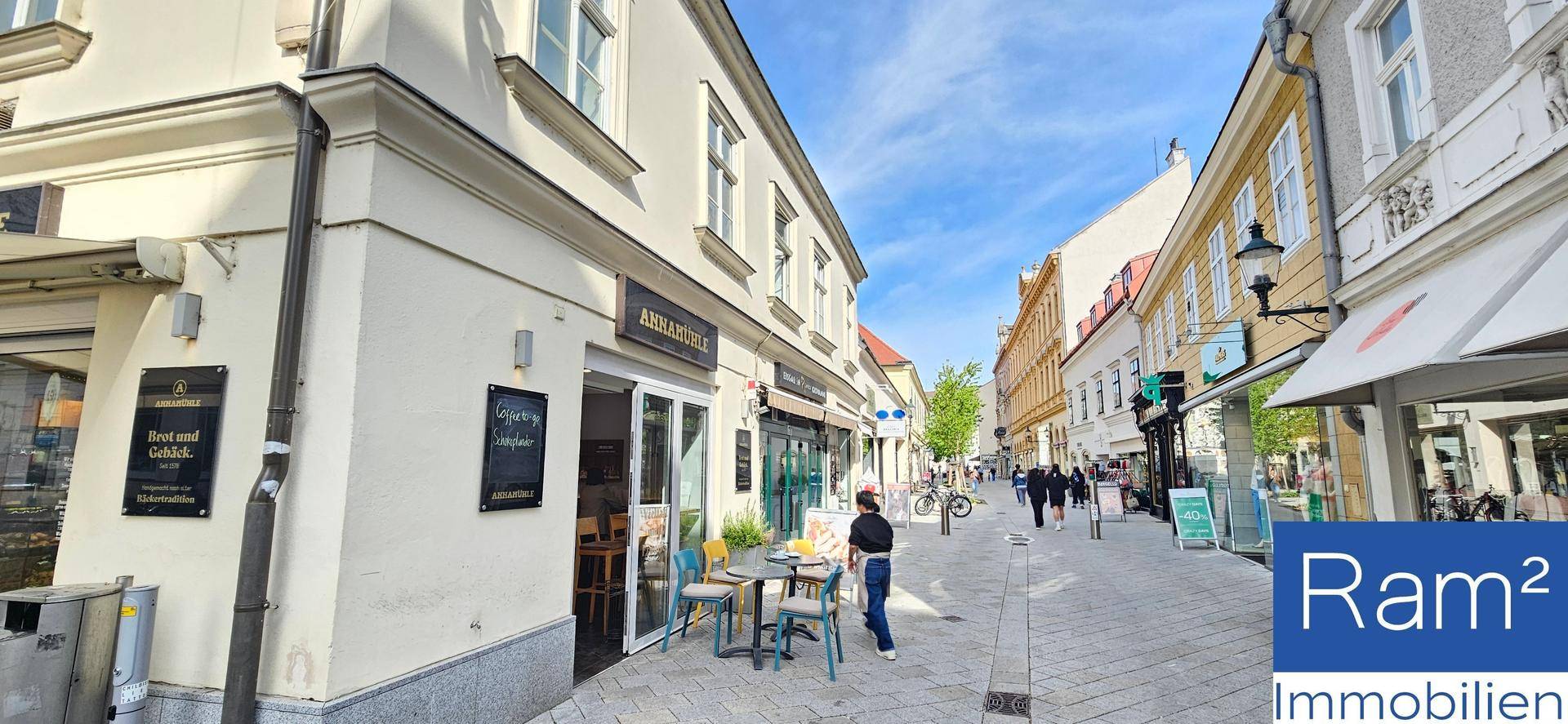 Ecke eines historischen Gebäudes mit Außengastronomie und belebter Fußgängerzone in der Stadt.