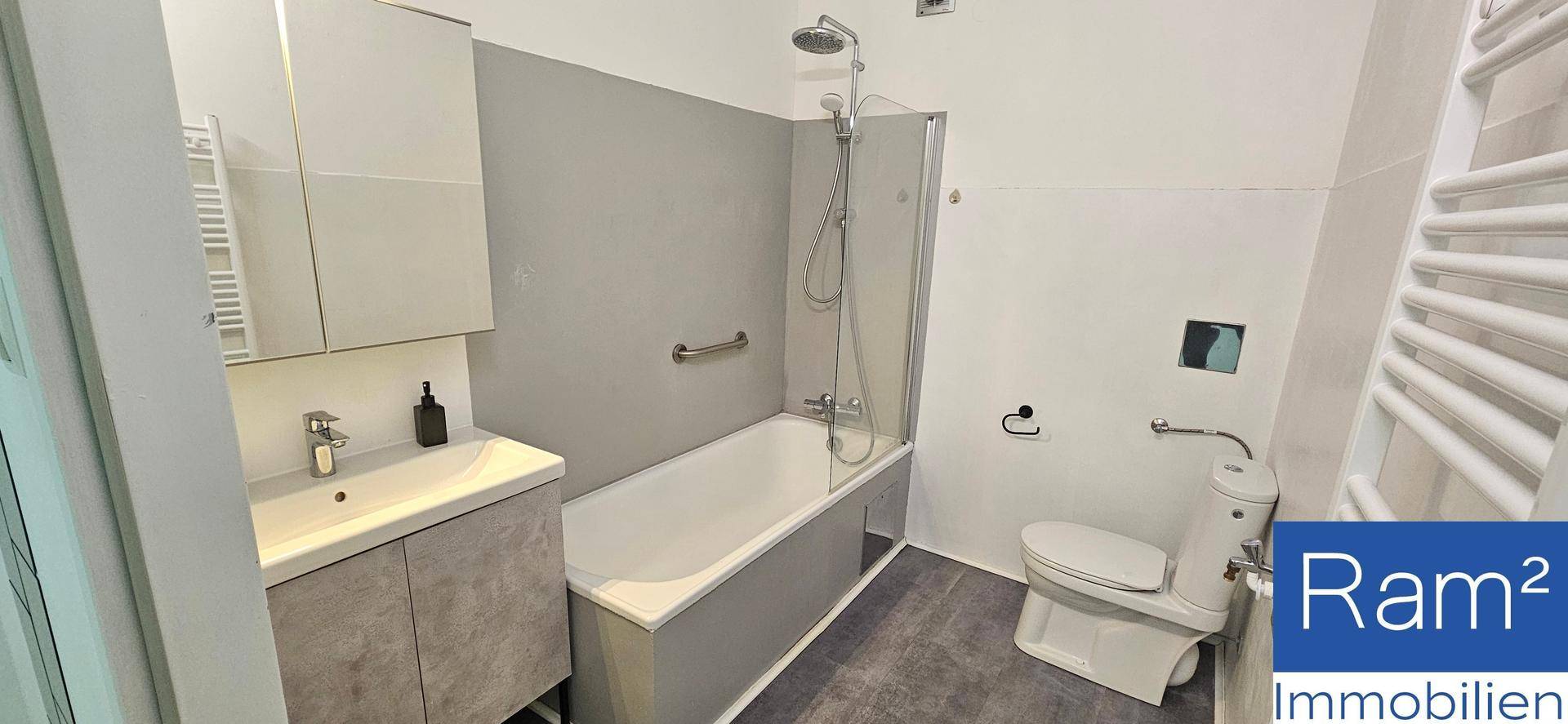 Modernes Badezimmer mit Badewanne, Dusche, WC und beheiztem Handtuchhalter.
