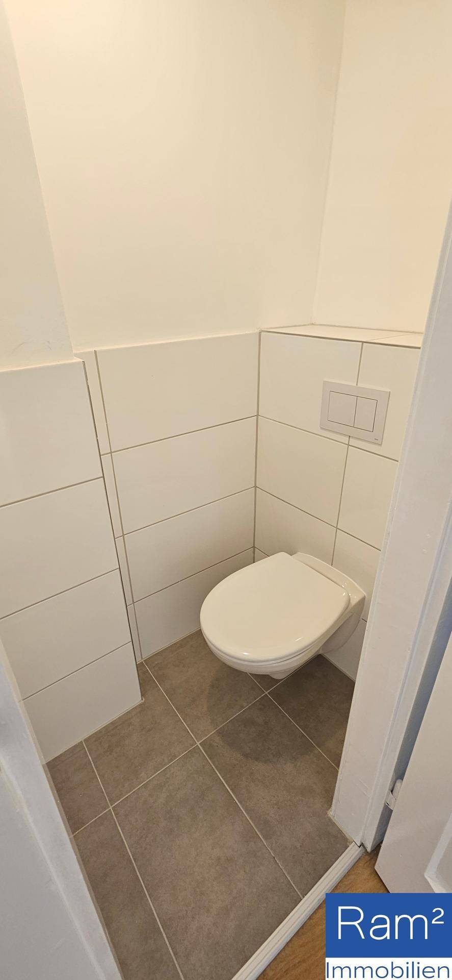 Separates WC mit modernen Fliesen und wandhängender Toilette.