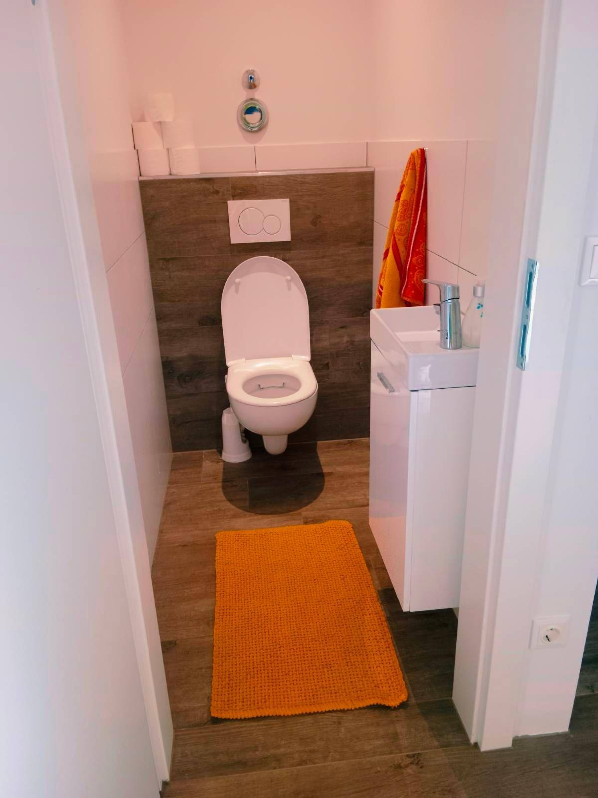 Kleines Gäste-WC mit wandhängender Toilette und einem kompakten Waschbecken.