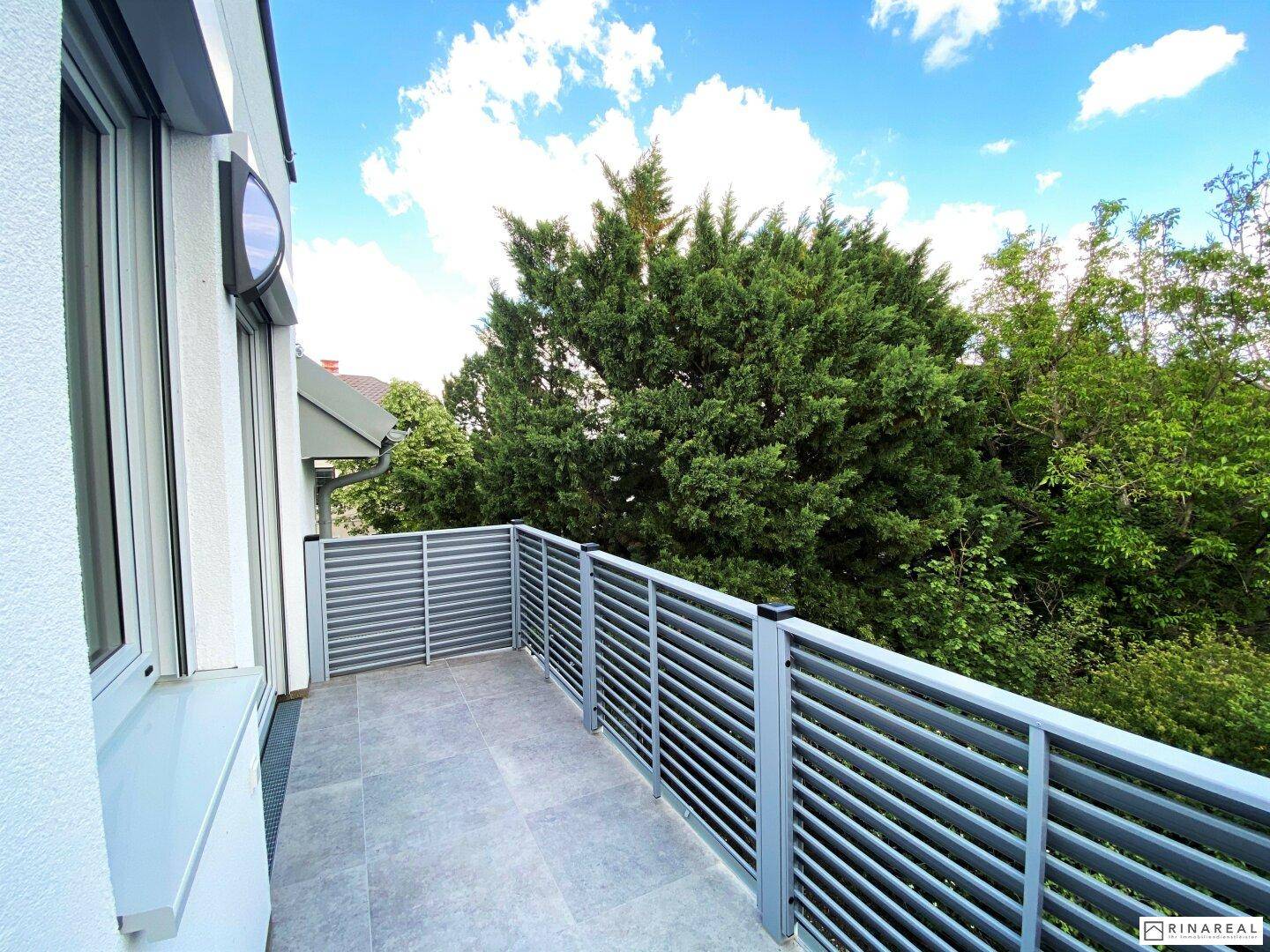 Geräumiger Balkon mit Fliesenboden und Blick ins Grüne, ideal zum Entspannen im Freien.