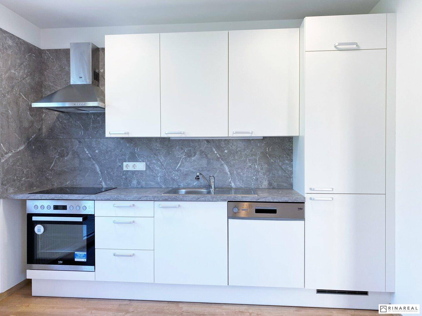 Moderne Einbauküche mit weißen Fronten, Induktionskochfeld und integrierten Geräten.