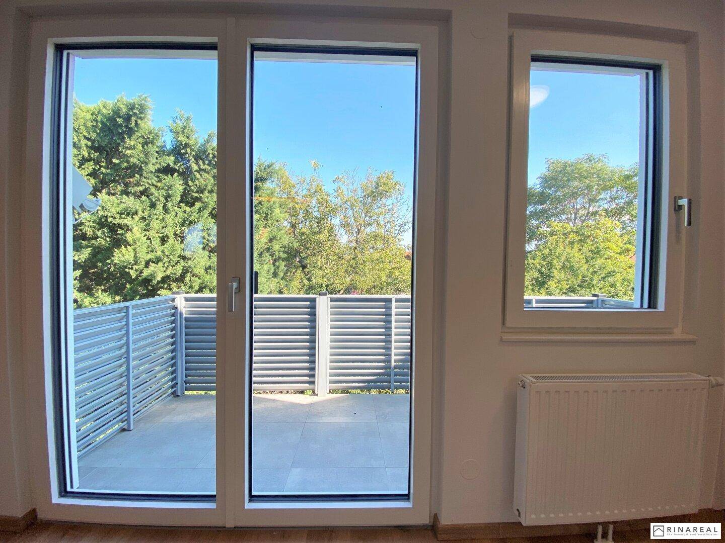 Große Fensterfront mit Zugang zum Balkon, die viel natürliches Licht in den Raum lässt.