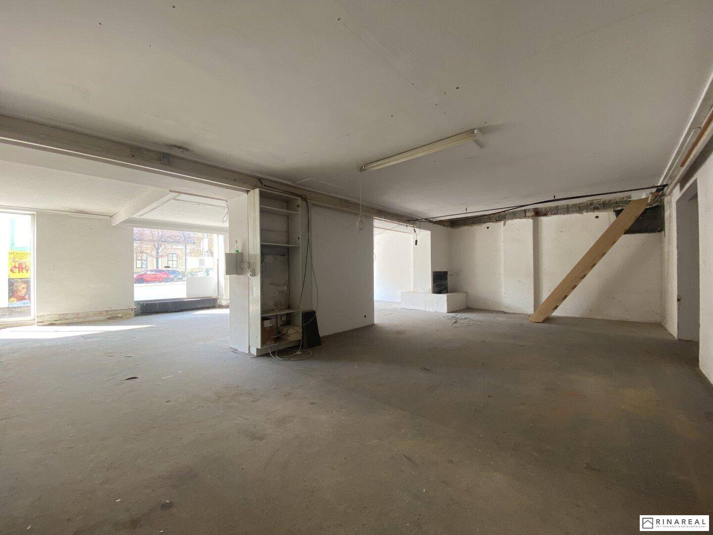 Weitläufiger, leerer Gewerberaum mit Betonboden und Blick auf die gesamte Fläche, ideal für individuelle Gestaltung.