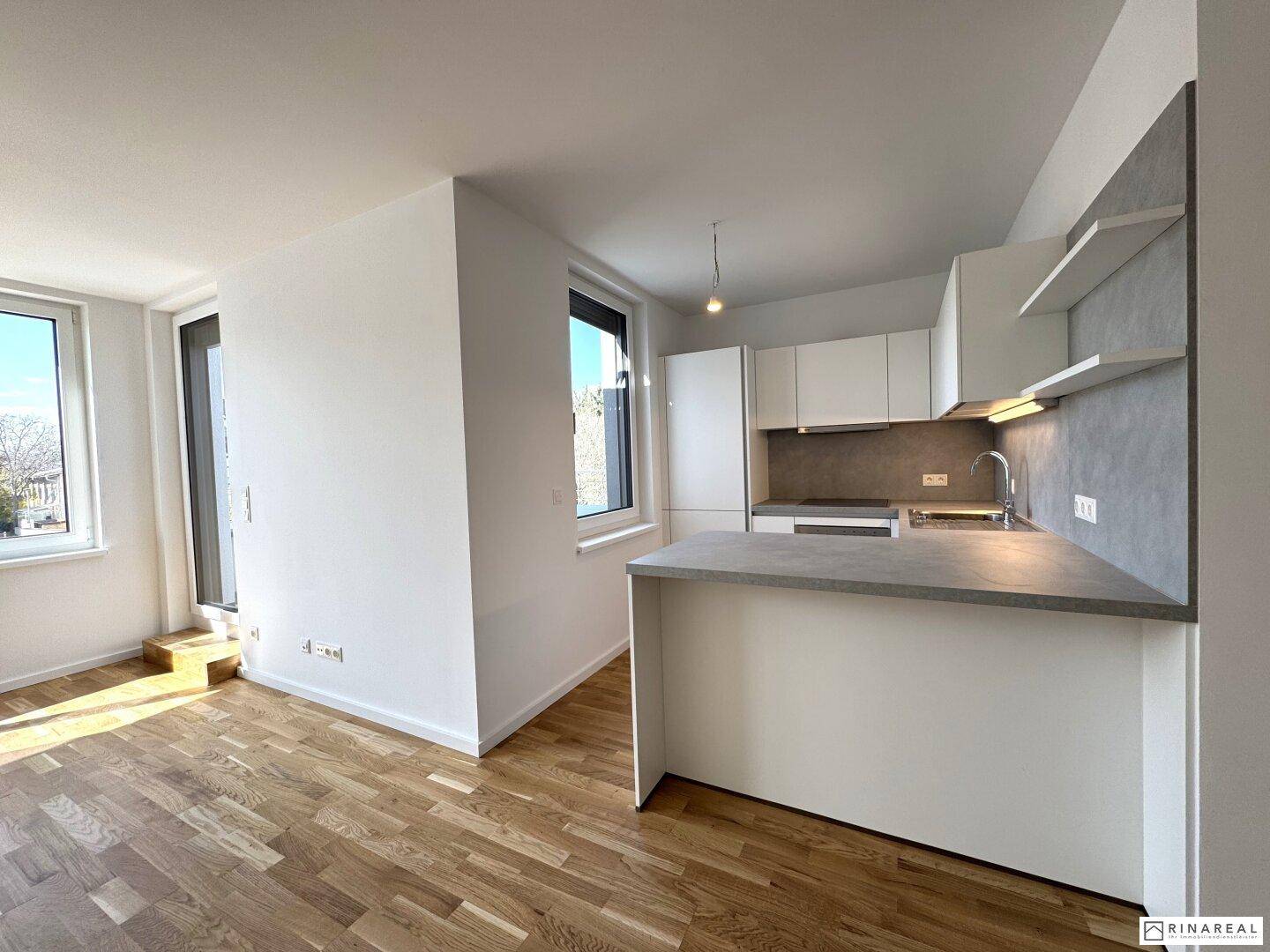 Offener Wohn- und Küchenbereich mit Parkettboden und viel natürlichem Licht, ideal für modernes Wohnen.