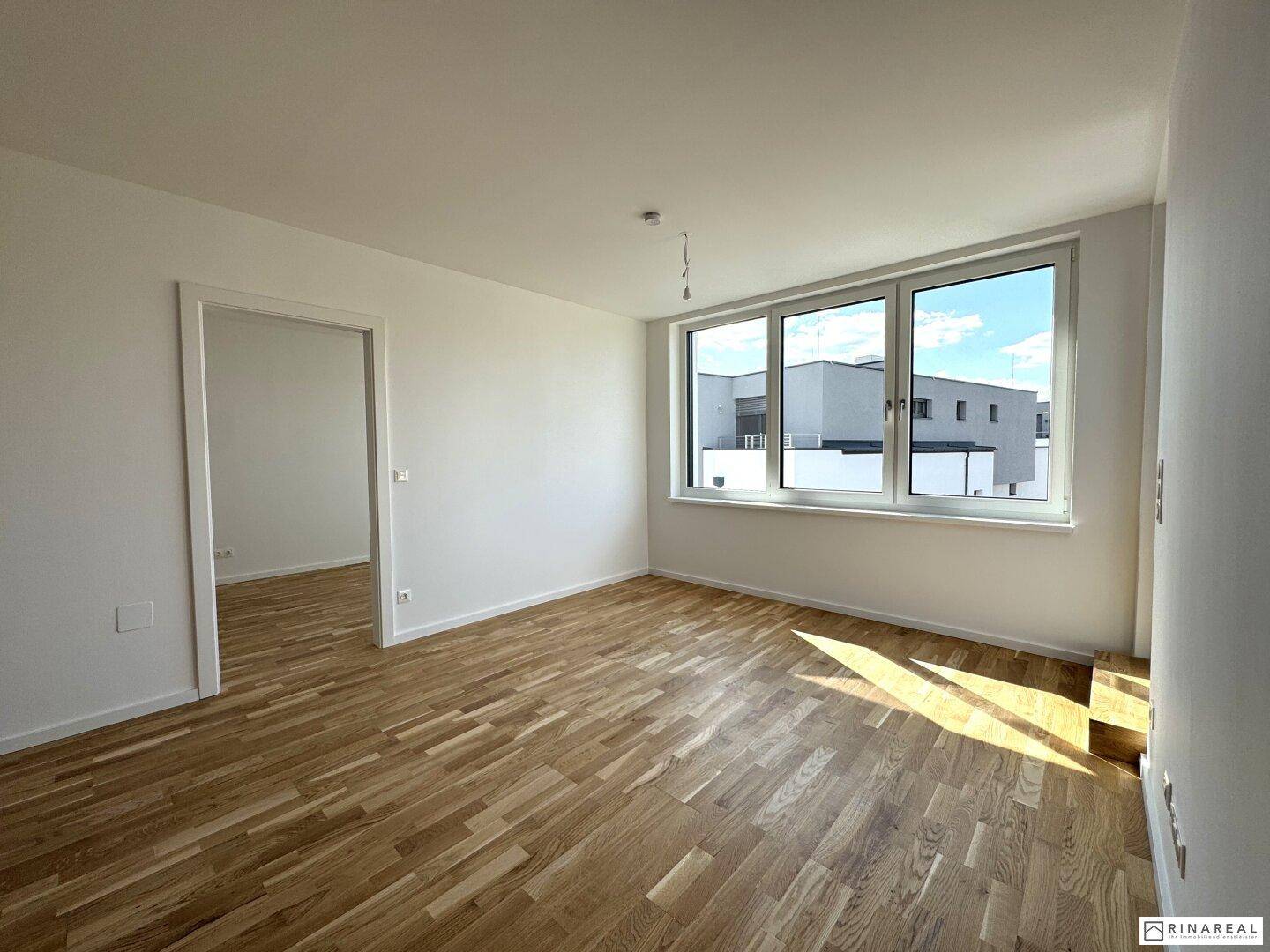 Lichtdurchflutetes Wohnzimmer mit Holzboden und großen Fenstern, die viel Helligkeit bieten, einladend und modern.