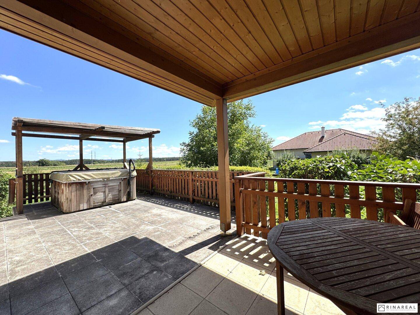 Geräumige Terrasse mit Holzdach, Esstisch und Whirlpool, ideal für Entspannung im Freien.