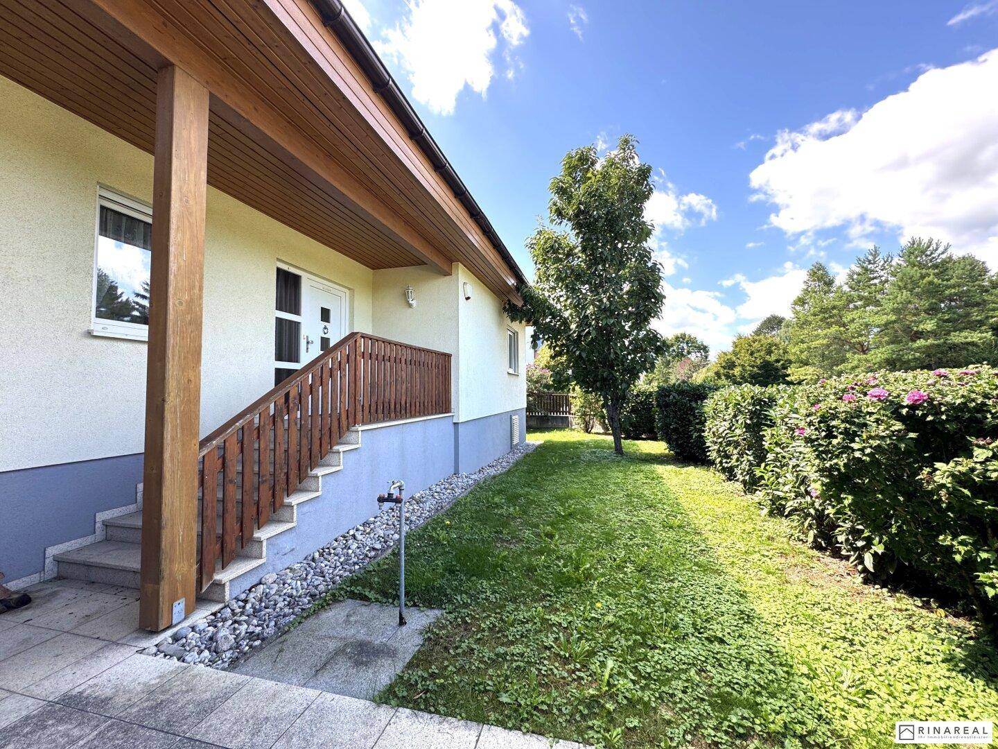 Eingangsbereich des Hauses mit Treppe, umgeben von gepflegtem Rasen und Hecken.