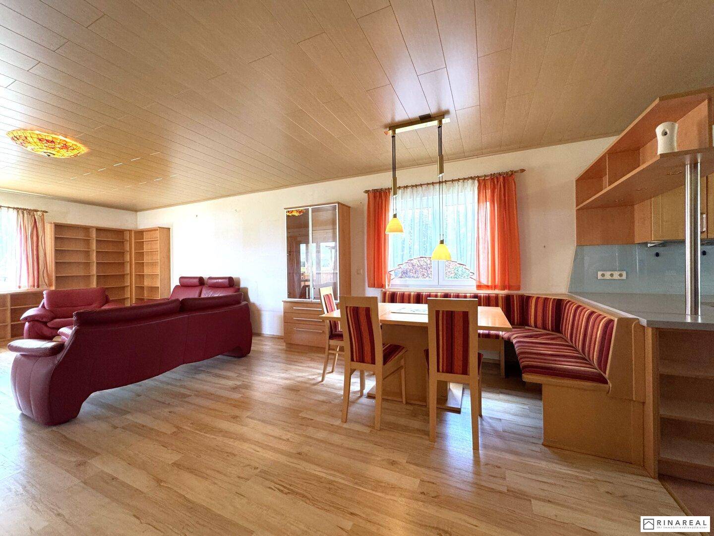 Geräumiger Wohn- und Essbereich mit Holzboden, rotem Sofa und traditioneller Essecke.