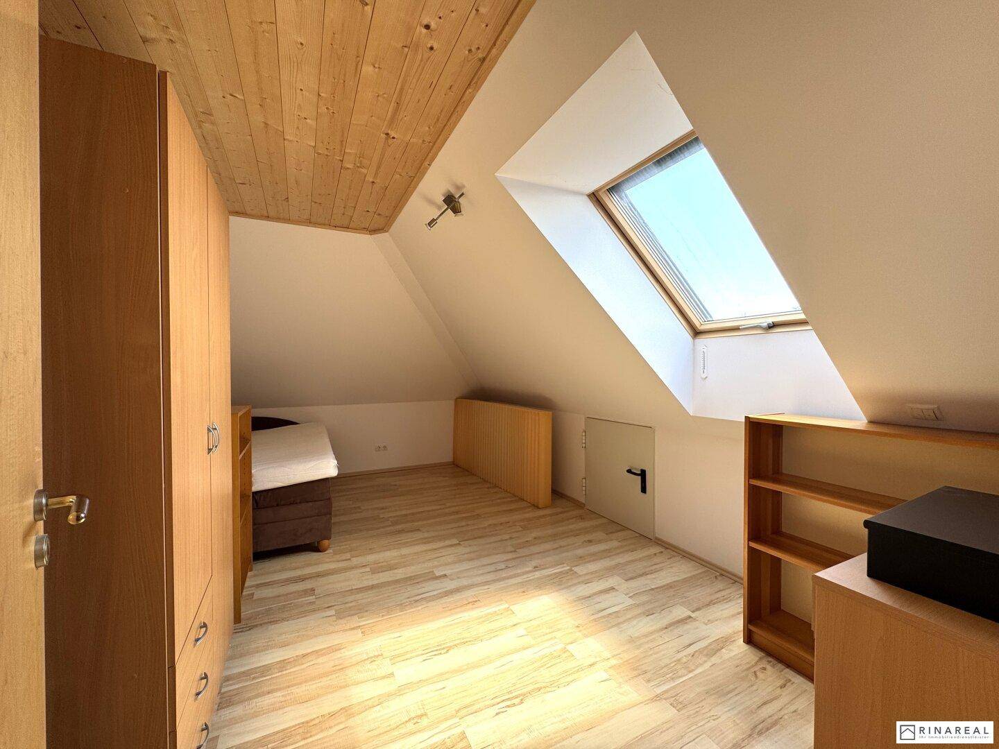 Gemütliches Schlafzimmer im Dachgeschoss mit Holzdecke, Laminatboden und Dachfenster.