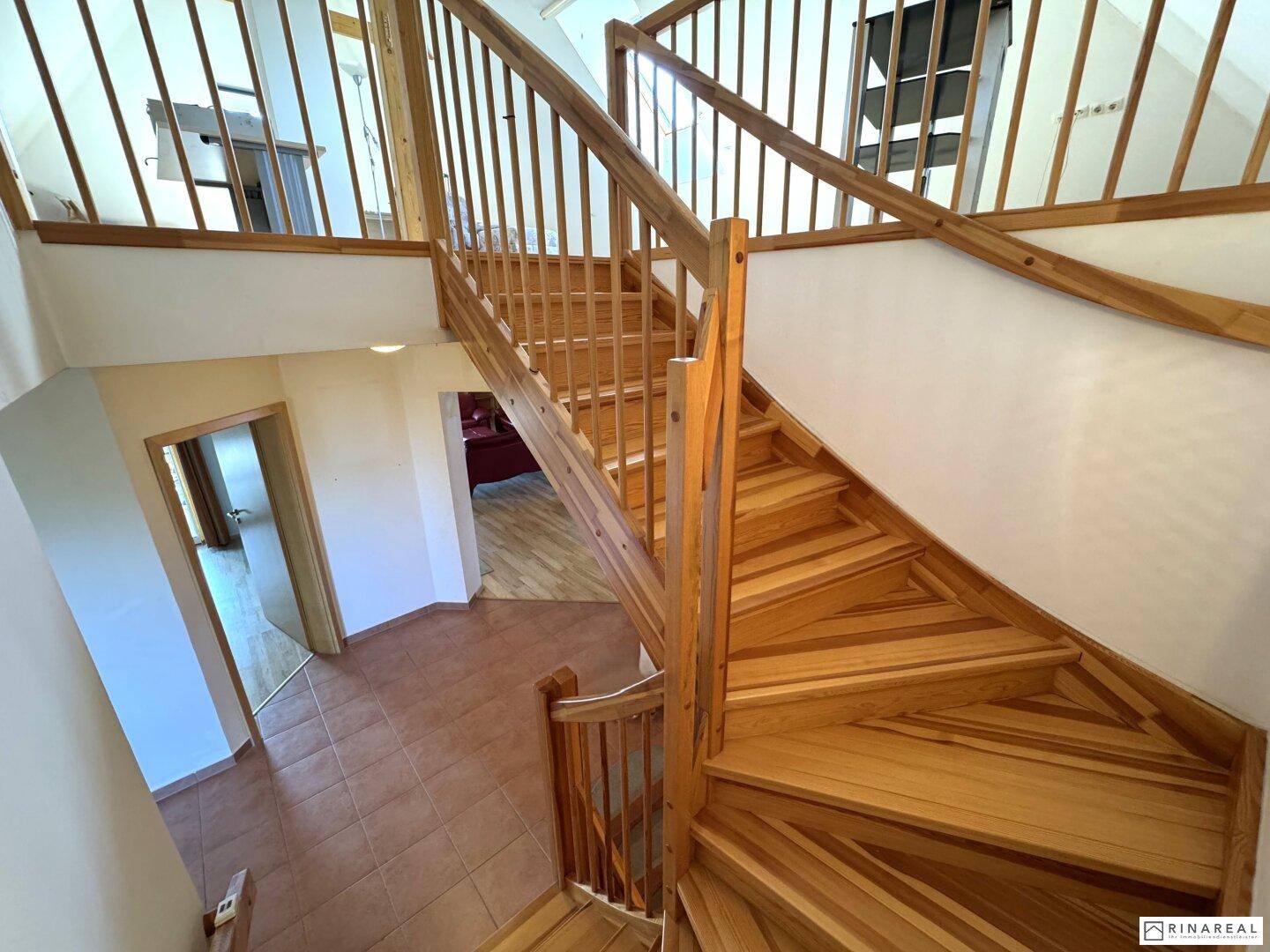 Holztreppe führt in die obere Etage, mit Blick auf den gefliesten Eingangsbereich.