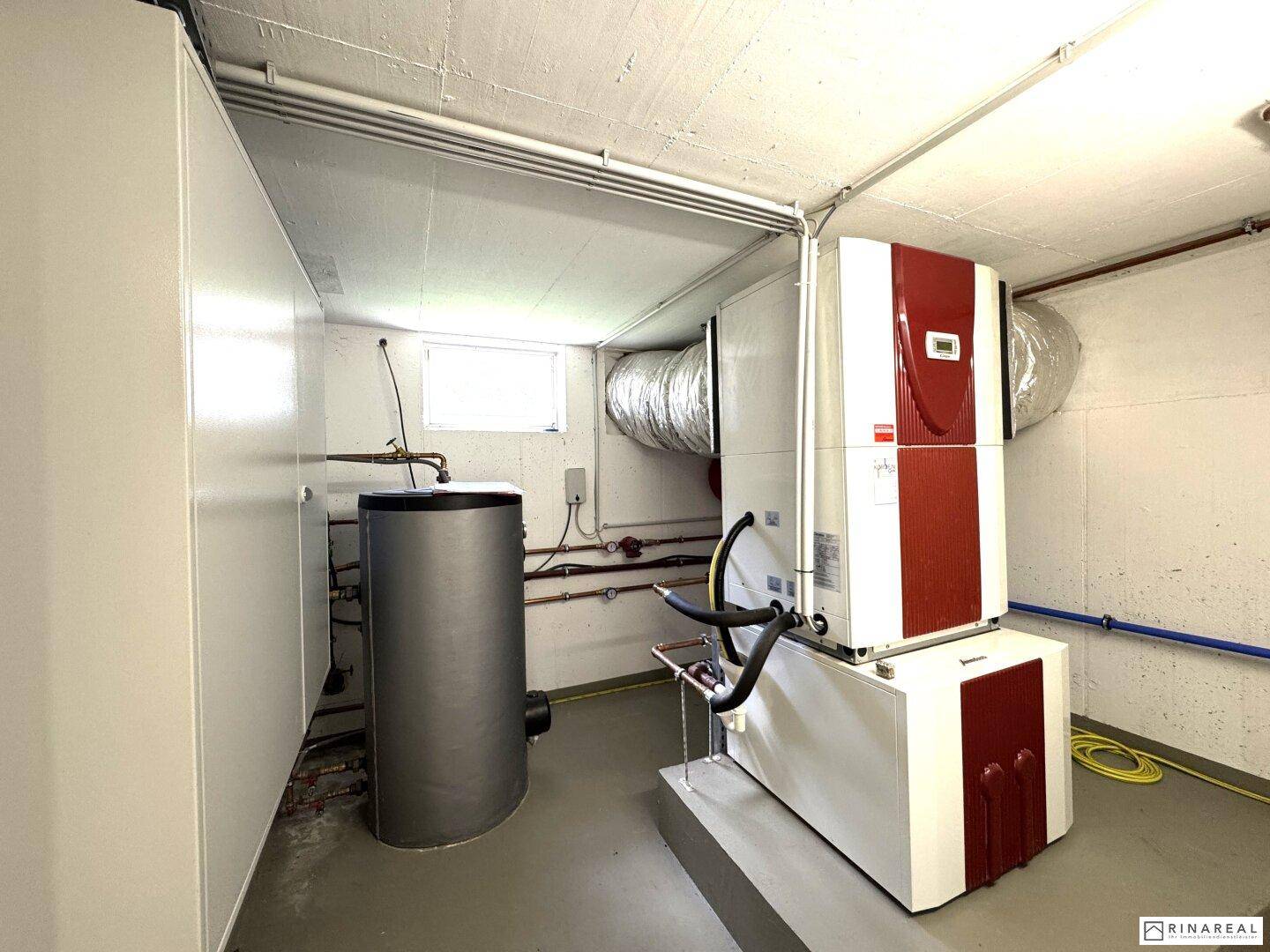Technikraum im Keller mit moderner Heizungsanlage, Warmwasserspeicher und Lüftungssystem.