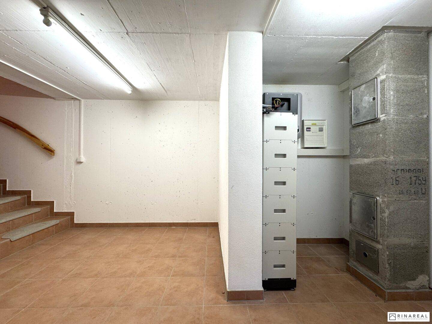 Geräumiger Kellerbereich mit gefliestem Boden, Treppenzugang und gemauertem Ofen oder Heizungszugang.