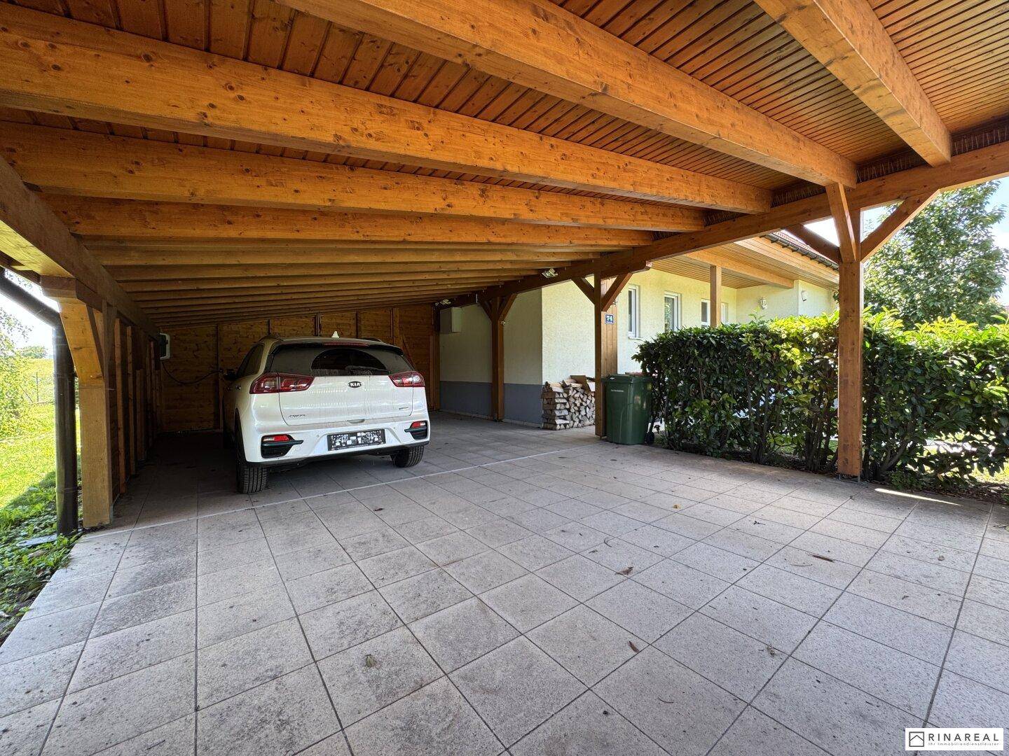 Geräumiger Holzcarport mit gepflastertem Boden bietet geschützten Stellplatz für ein Fahrzeug.