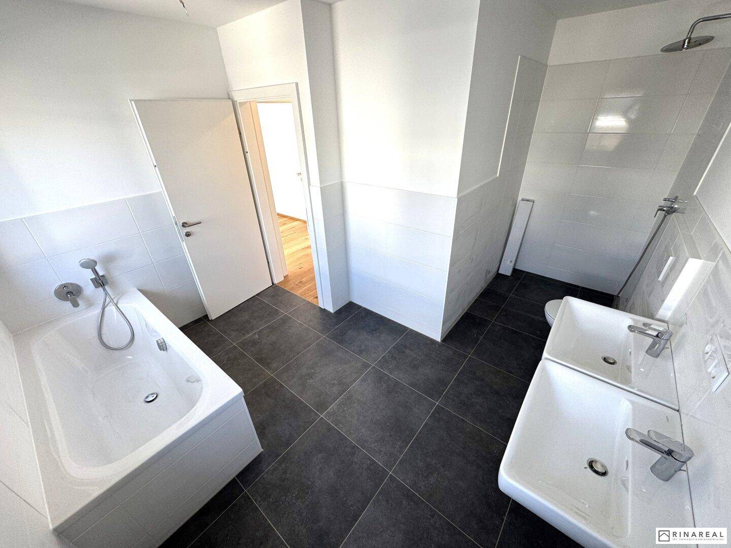 Geräumiges Badezimmer mit Badewanne, Duschbereich und Doppelwaschbecken, alles in modernem Stil.