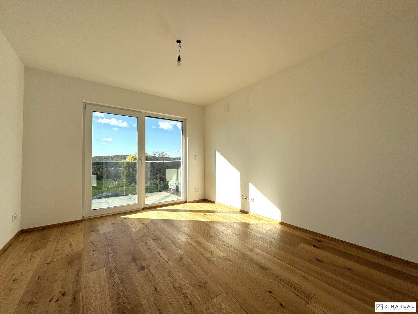 Helles Schlafzimmer mit Holzboden und Zugang zu einem Balkon mit Weitblick.