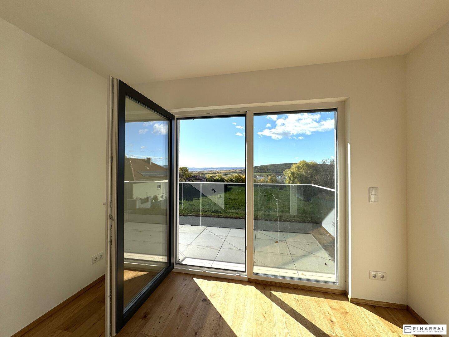 Lichtdurchflutetes Schlafzimmer mit Holzboden und direktem Zugang zum Balkon.