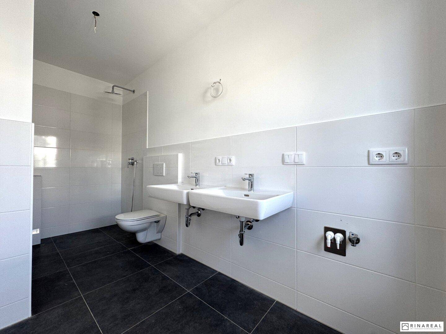 Modernes Badezimmer mit Doppelwaschbecken, wandhängendem WC und Duschbereich.