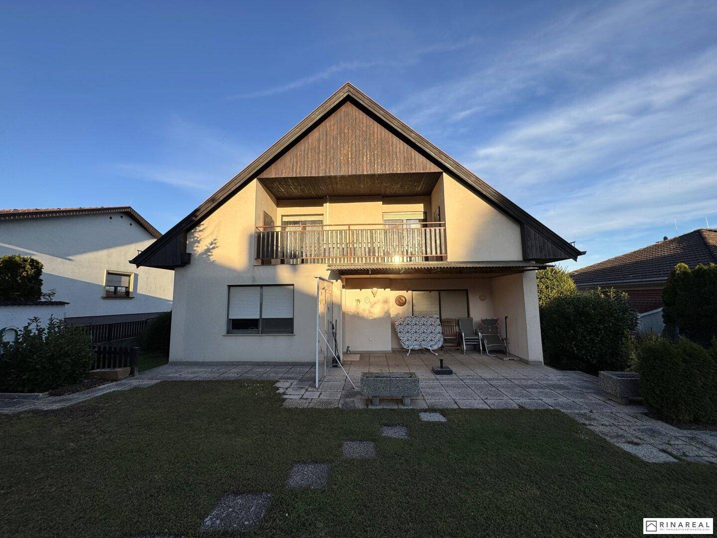 Rückseite des Hauses mit überdachter Terrasse im Erdgeschoss und Balkon im Obergeschoss.