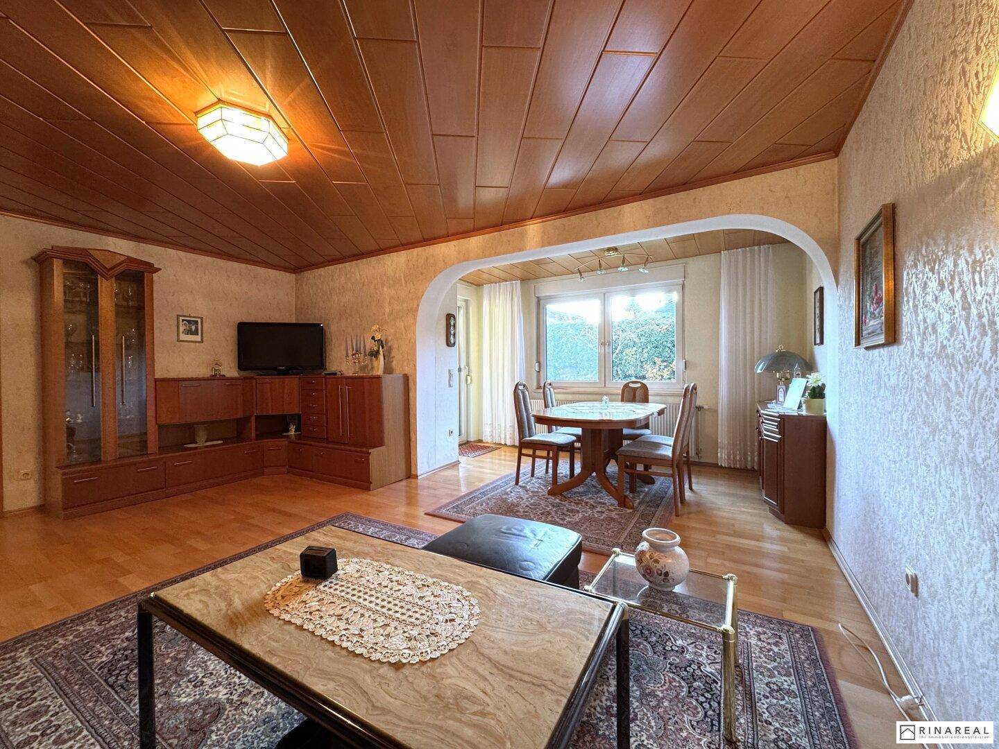 Geräumiges Wohnzimmer mit Parkettboden, Holzdecke und traditioneller Einrichtung.