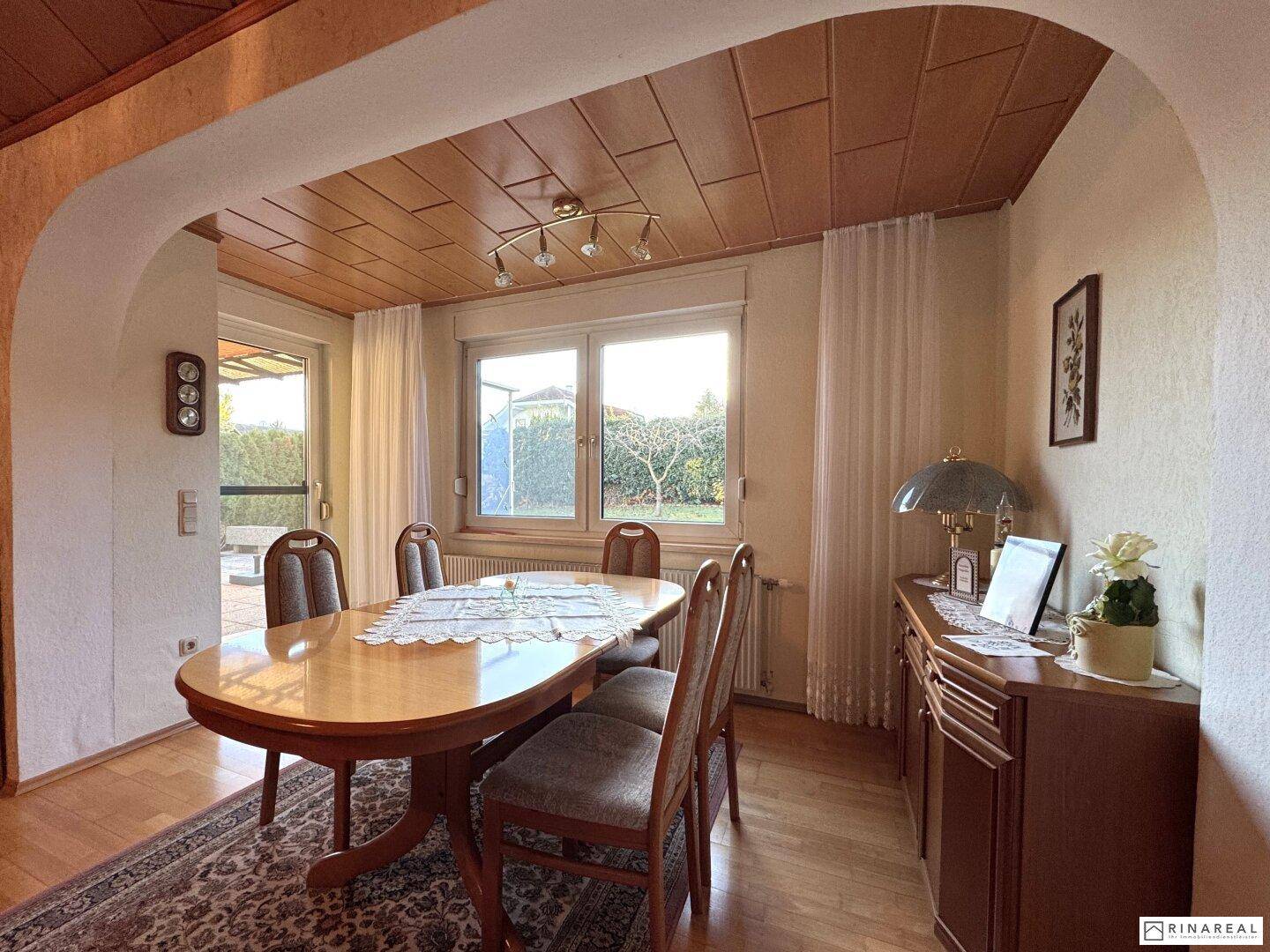 Heller Essbereich mit Holztisch, Stühlen und Blick in den Garten.