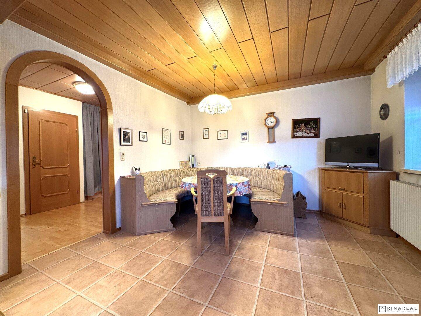 Gemütlicher Essbereich mit Eckbank, Fliesenboden und Holzdecke.