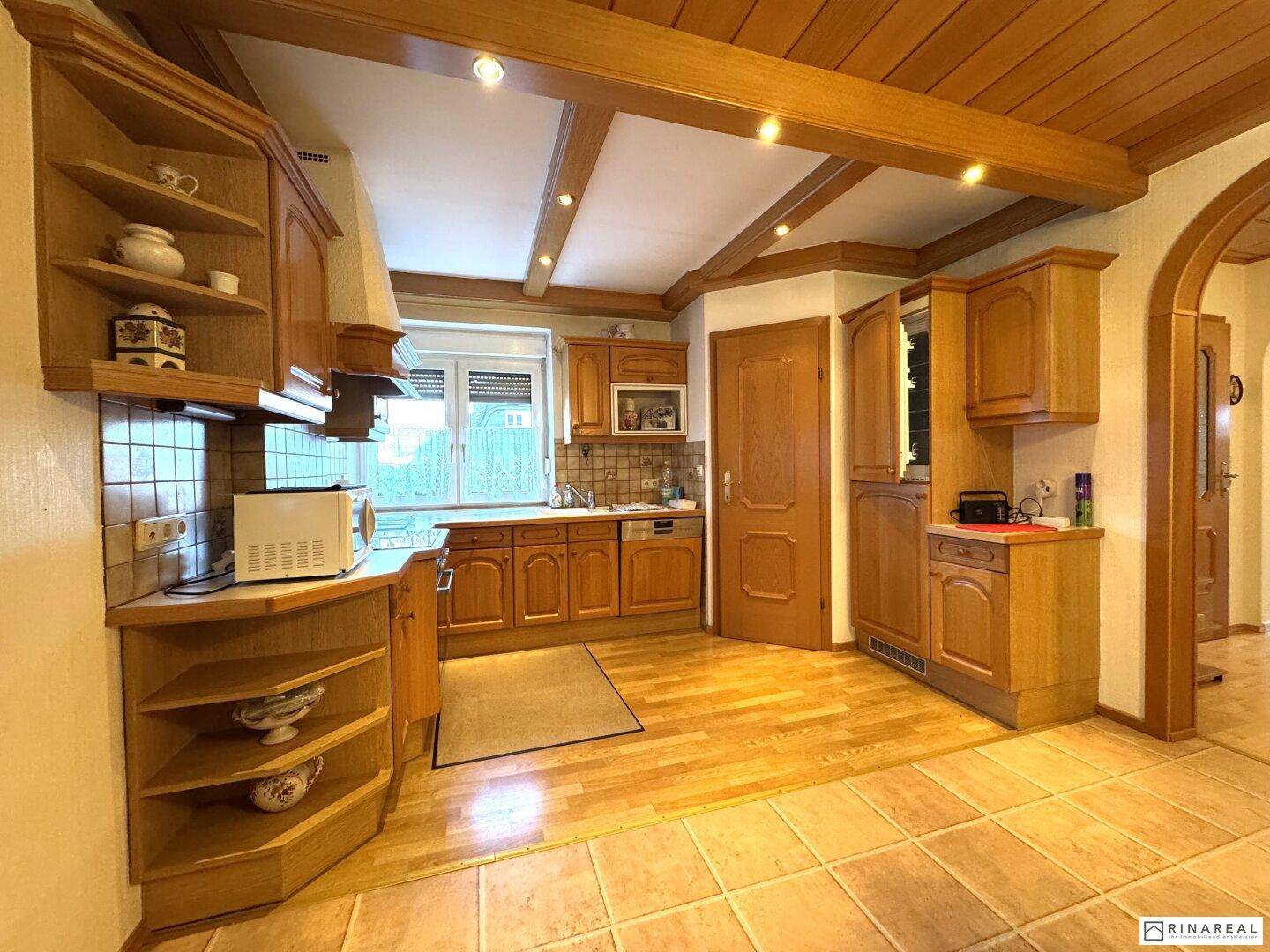 Traditionelle Küche mit Holzschränken, Einbaugeräten und Fenster mit Blick ins Grüne.