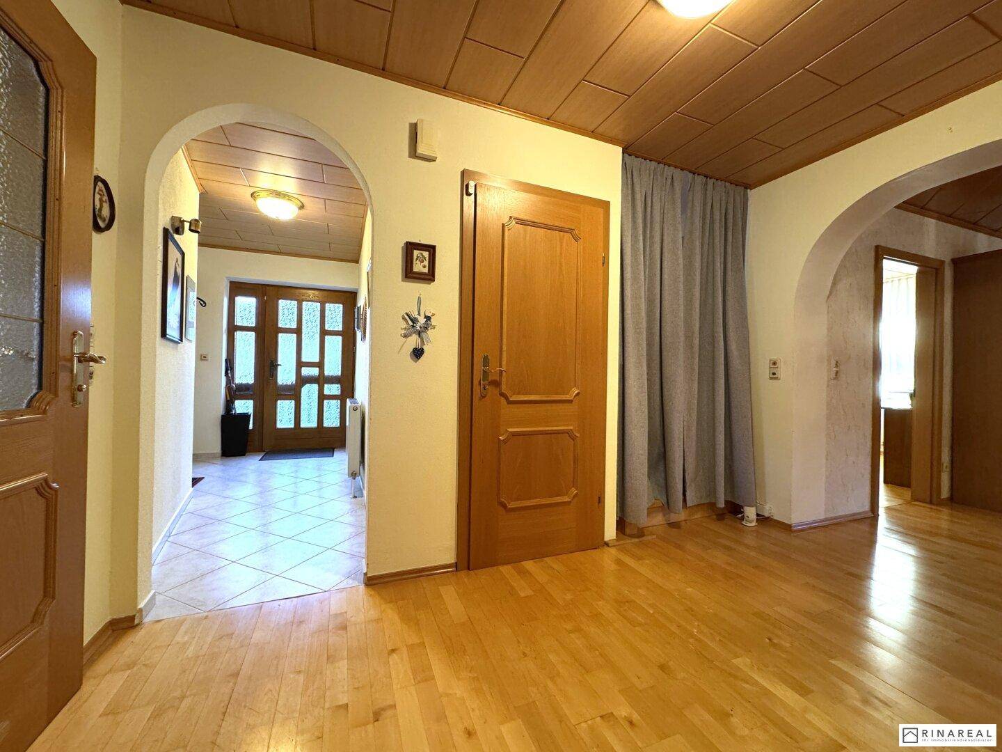 Geräumiger Flur mit Holzparkettboden, Holztüren und Zugang zu weiteren Räumen.