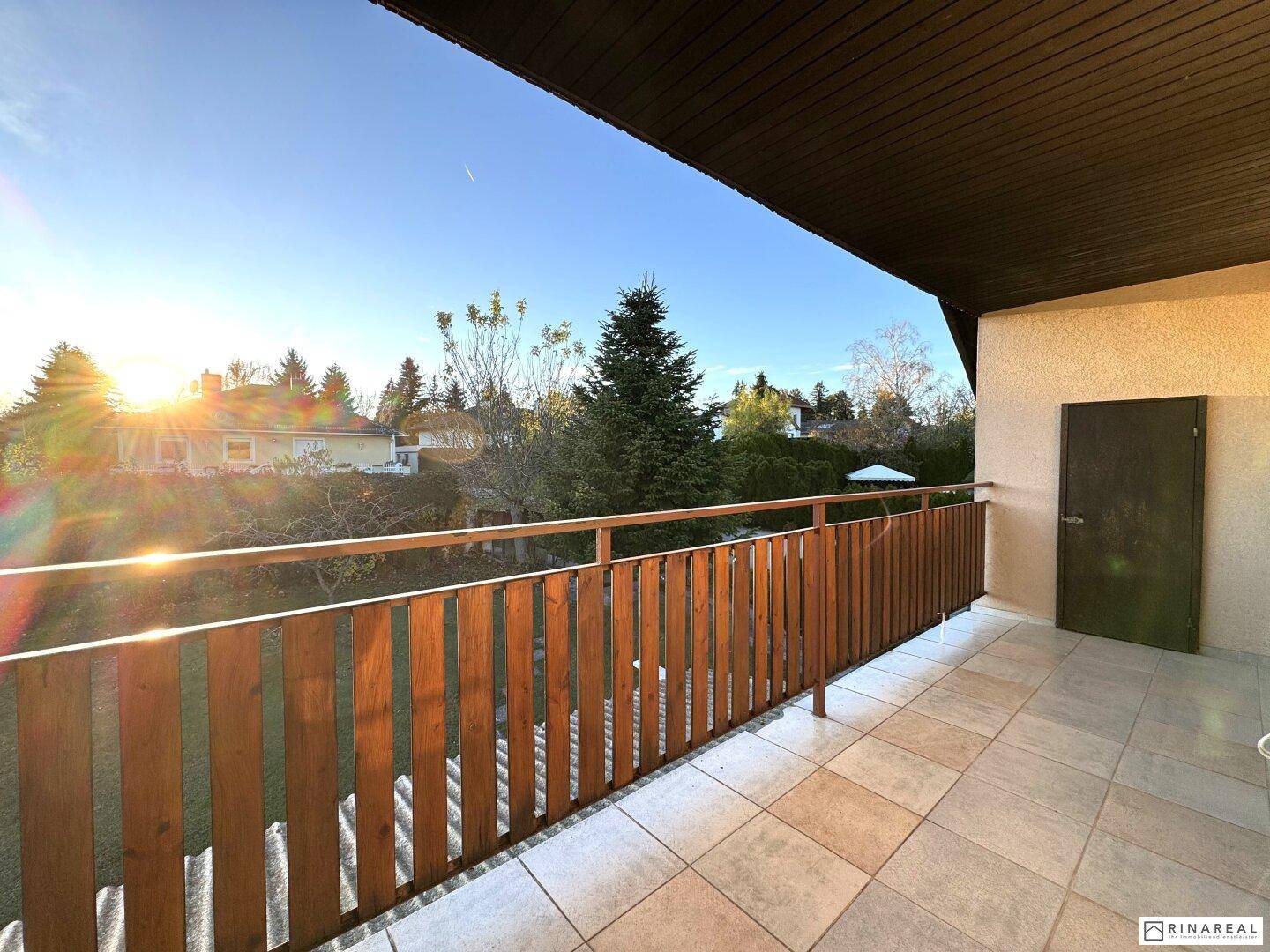 Geräumiger Balkon mit Fliesenboden und Holzgeländer, bietet weite Aussicht.
