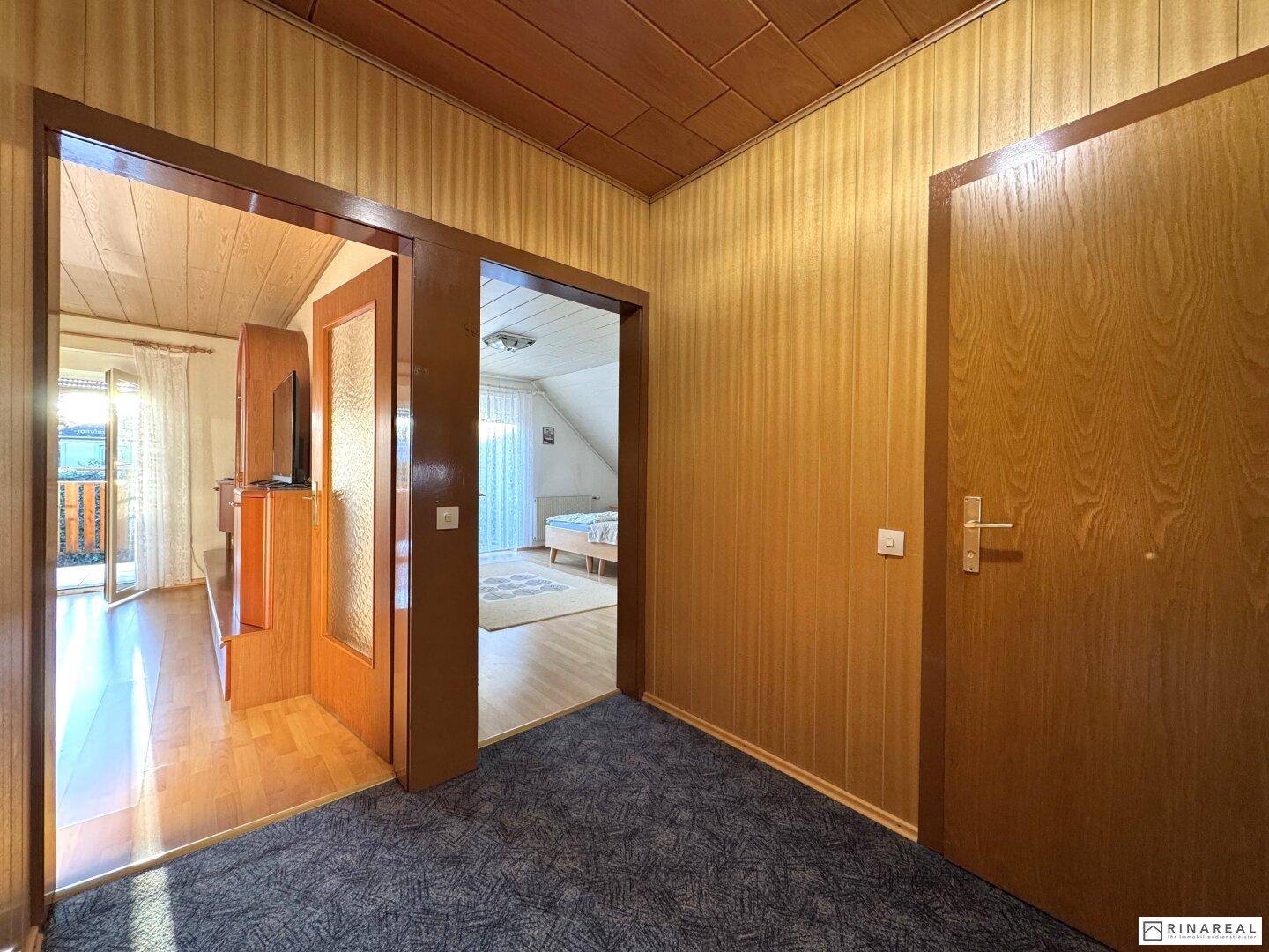 Flur im Obergeschoss mit Teppichboden, Holzvertäfelung und Zugang zu weiteren Räumen.