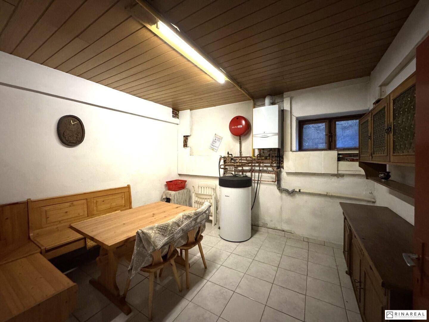 Kellerraum mit Heizungsanlage, Fliesenboden und einfacher Einrichtung.