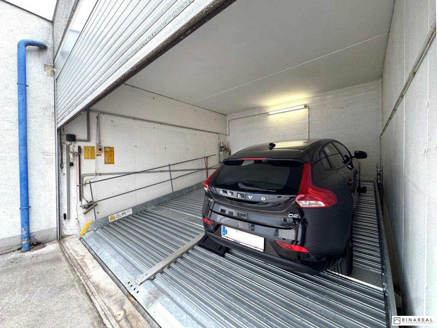 Innenansicht eines Garagenstellplatzes mit einem geparkten Fahrzeug auf der unteren Ebene des Parksystems.