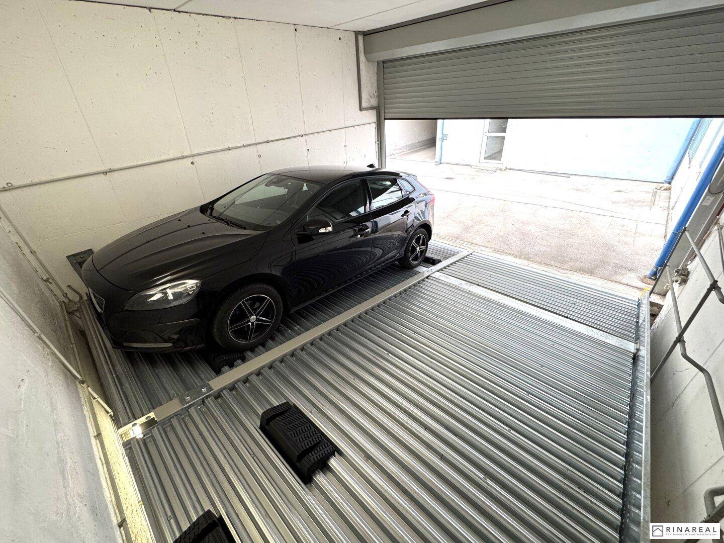 Innenansicht eines Garagenstellplatzes mit einem Fahrzeug auf der unteren Parkebene und freier oberer Ebene.