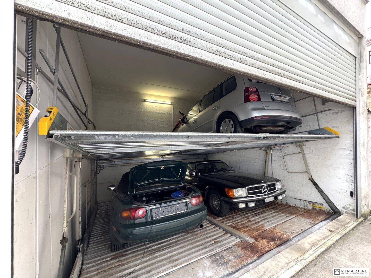 Innenansicht des zweiten Garagenstellplatzes mit drei Fahrzeugen auf zwei Ebenen des Parksystems.