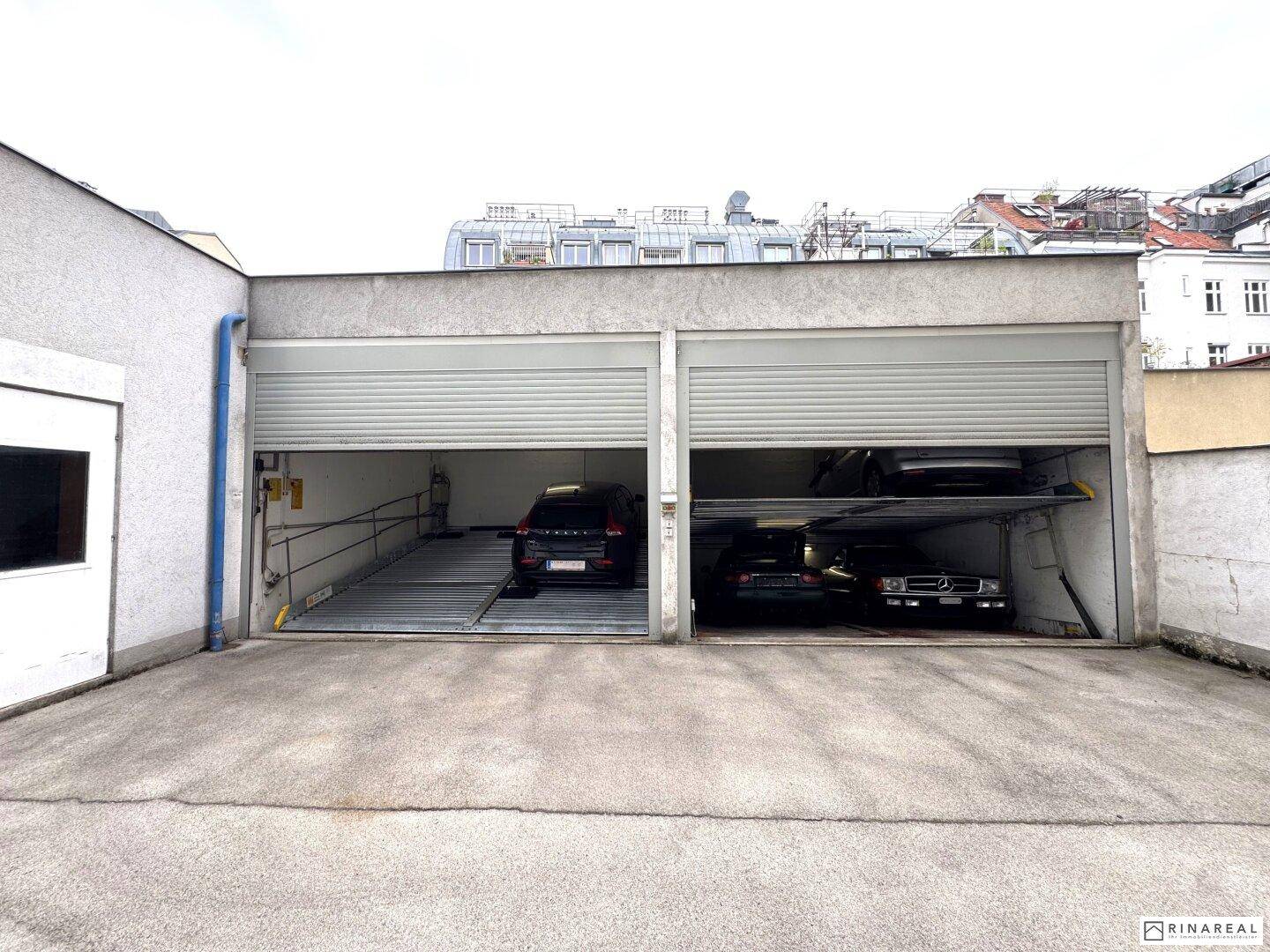 Außenansicht der Tiefgarage mit zwei Stellplätzen und automatischen Parksystemen für mehrere Fahrzeuge.