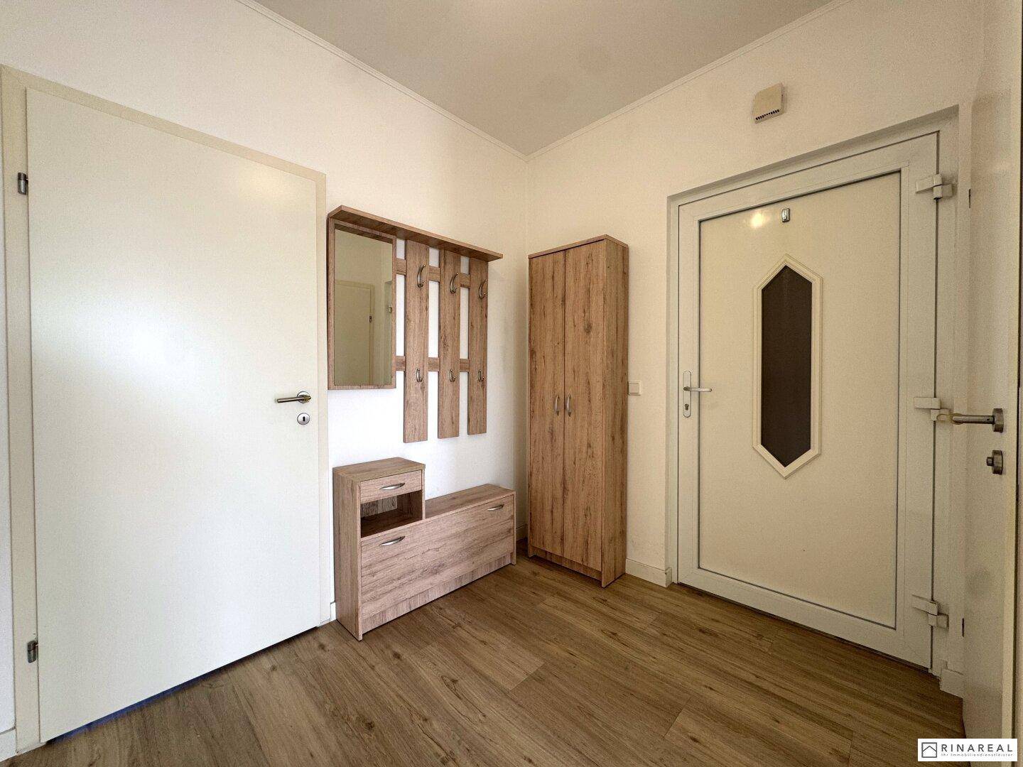 Eingangsbereich mit Garderobe, Schuhschrank und heller Holzlaminatboden.