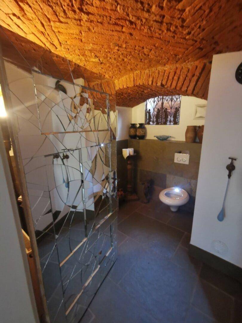 Einzigartiges WC mit Ziegelgewölbe, Steinboden und einem modernen Wand-WC.