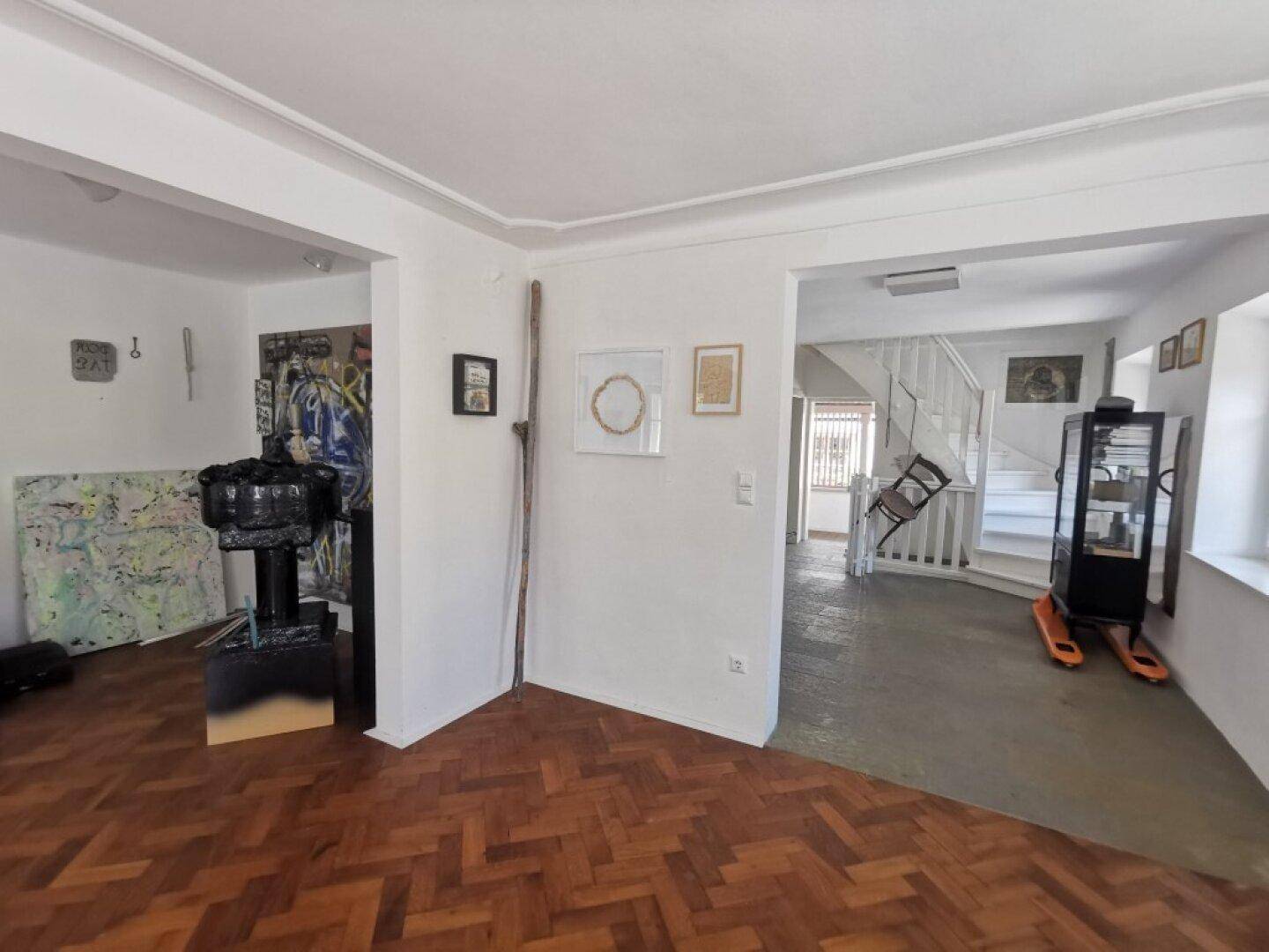 Übergangsbereich mit Fischgrätparkett, der zu einer Treppe und weiteren Räumen führt.