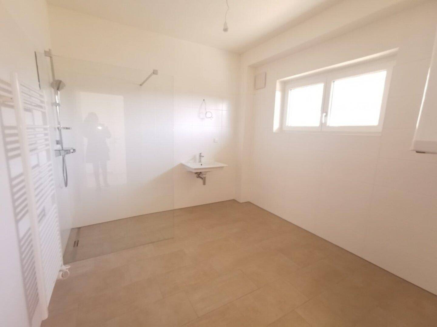 Modernes Badezimmer mit begehbarer Dusche, Fenster und beheiztem Handtuchhalter.