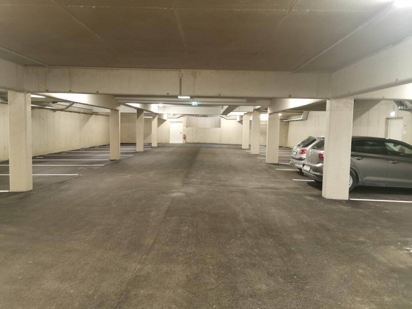 Geräumige Tiefgarage mit vielen Stellplätzen und Betonstützen für Bewohner.